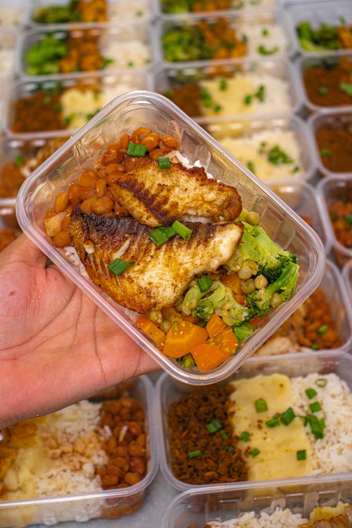 A nutritious meal prep box featuring grilled fish, broccoli, and beans for a balanced diet.