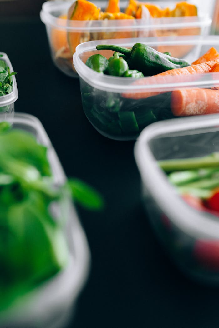 Close-up view of assorted fresh vegetables stored in plastic containers preserving freshness.